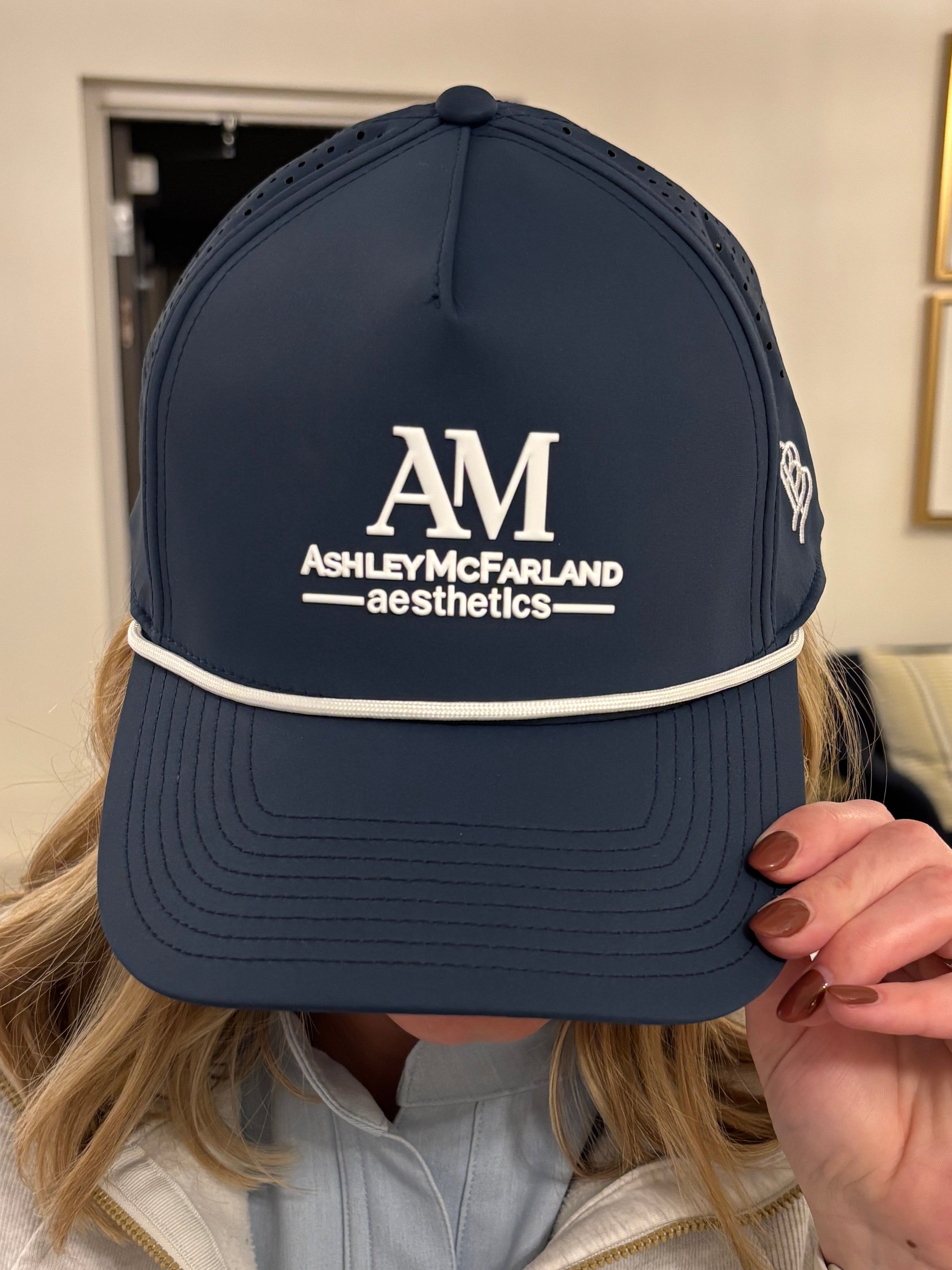Person wearing a navy cap with 'AM' logo in an indoor setting